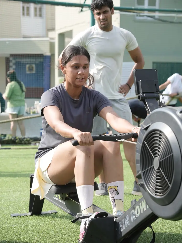 A participant mid-pull on the air rower while others queue behind
